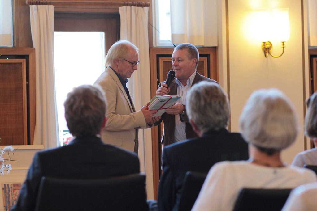 Peter Schümann, Vorsitzender der Stadtteilbücherei Neumühlen-Dietrichsdorf, übergibt ein Präsent.